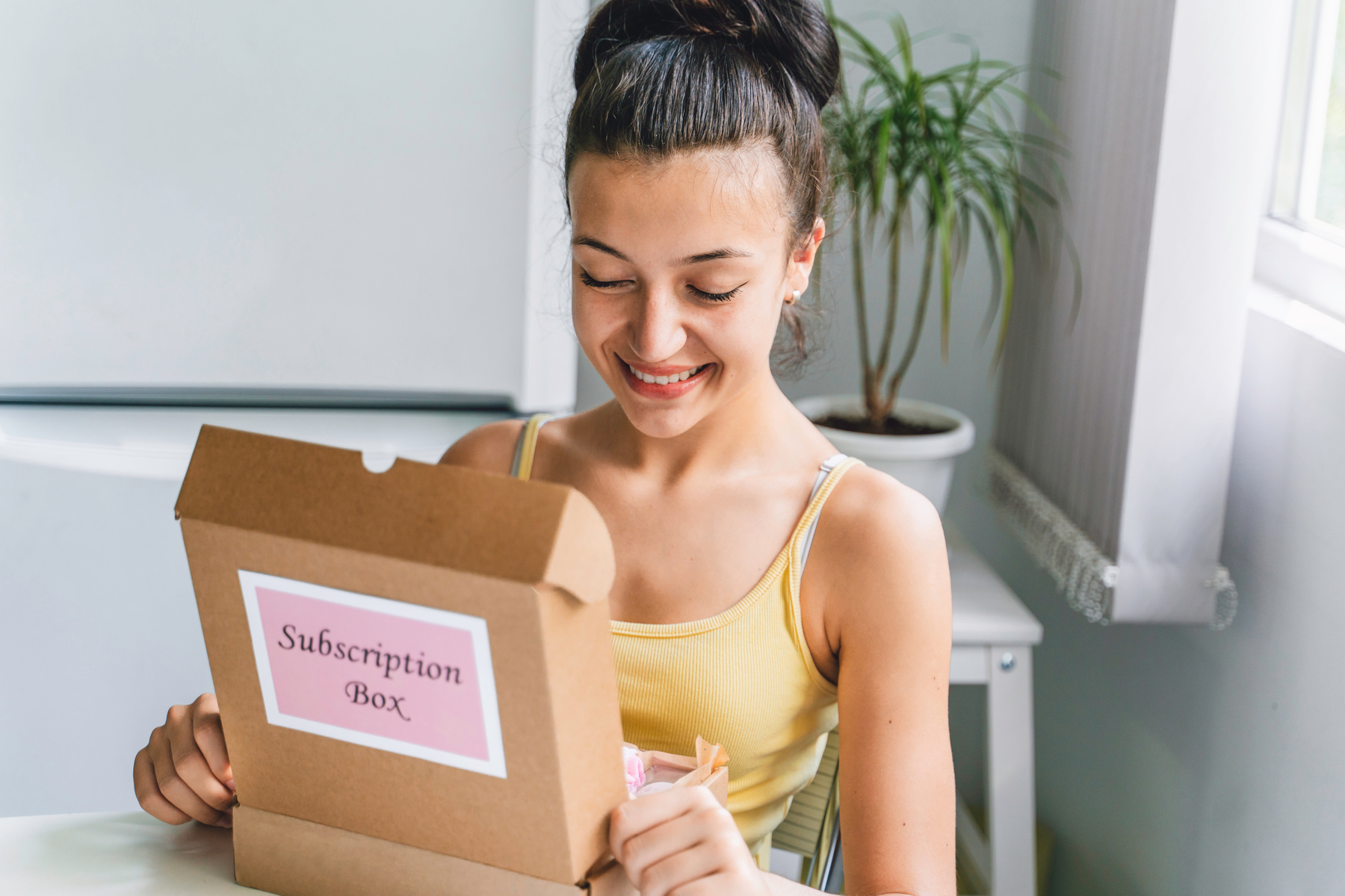 Beautiful girl opening Subscription box with beauty products.